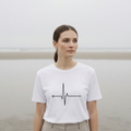 Woman wearing a white t-shirt with a black heartbeat design on a plain background.